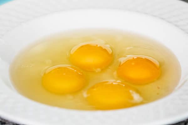 Four raw eggs with egg whites in bowl