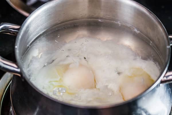 Eggs being poached in a pot of boiling water