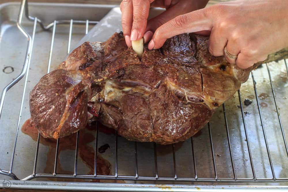 Inserting garlic pieces in leg of lamb