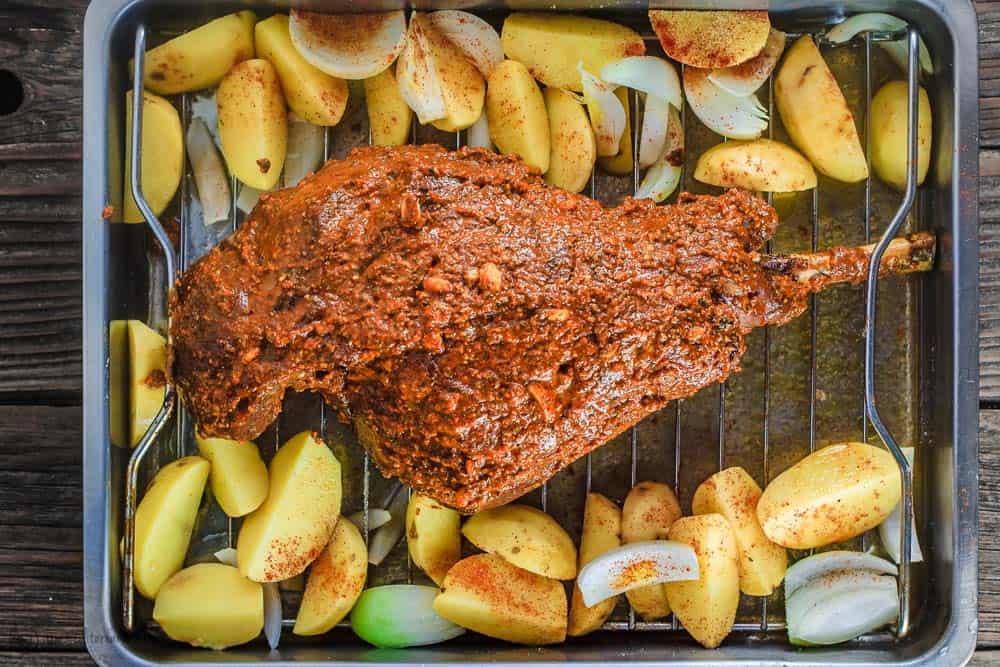 potatoes and leg of lamb that's covered in spice rub in roasting pan
