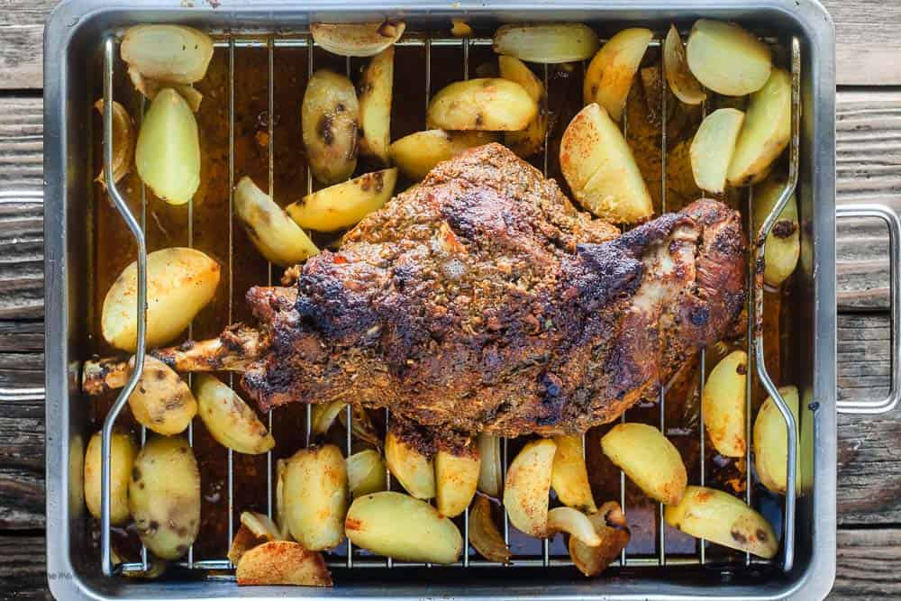 Roasted leg of lamb and potatoes in roasting pan 