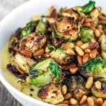 Fried Brussels Sprouts Recipe with Onions and Quick Polenta | The Mediterranean Dish. Crispy brussel sprouts fried in olive oil; served with Parmesan polenta and topped with toasted pine nuts. A 20-minute delicious side dish!