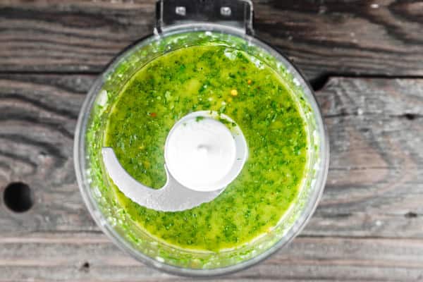 Ingredients of basil vinaigrette added to food processor and blended together