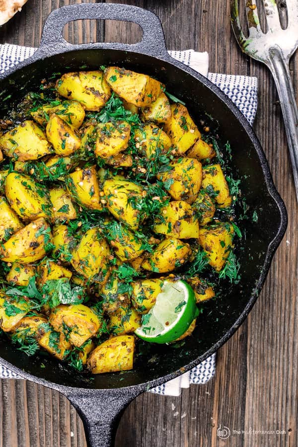 Batata Harra. Middle Eastern skillet potatoes garnished with fresh parsley, cilantro, dill and a lime wedge.