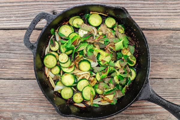 Zucchini, onions and mint added to a skillet