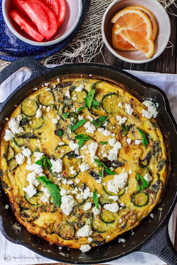 Omelet garnished with feta cheese and served with orange and tomato wedges