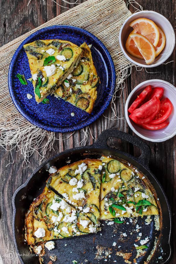 Two slices of Zucchini Omelet served with orange and tomato slices