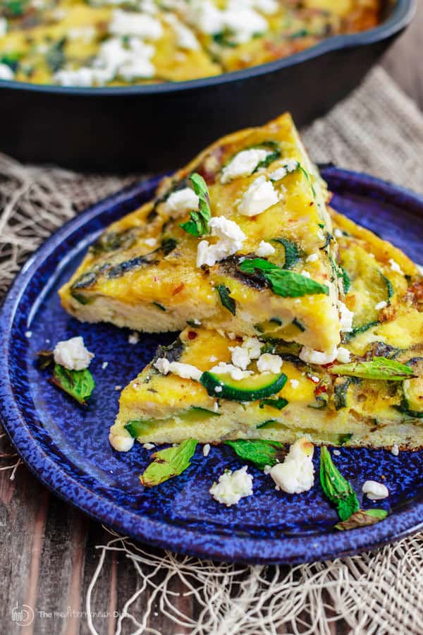 Slice of Middle Eastern Zucchini Baked Omelet garnished with basil leaves and feta cheese