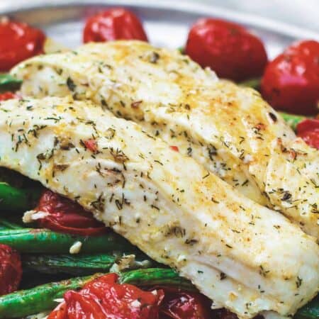 Baked halibut served in a plate with tomatoes and green beans