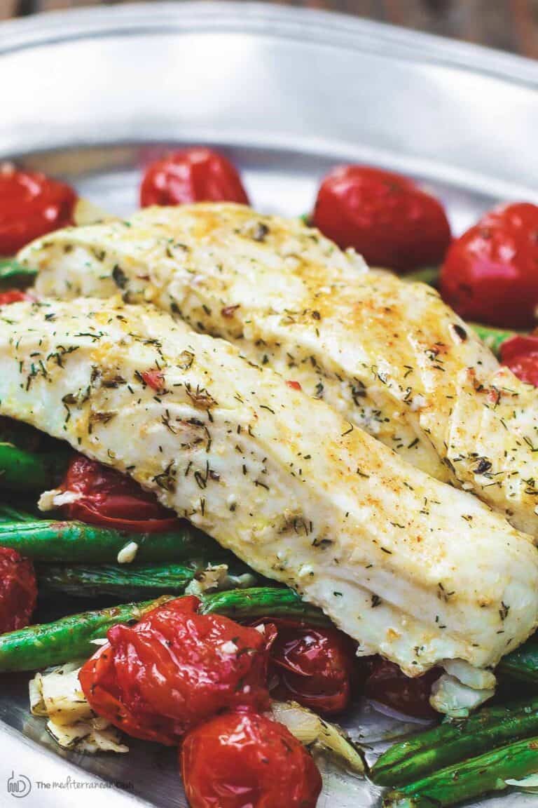 Baked halibut served in a plate with tomatoes and green beans