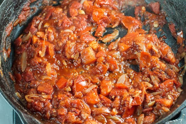 Harissa paste and onions cooking together in a pan