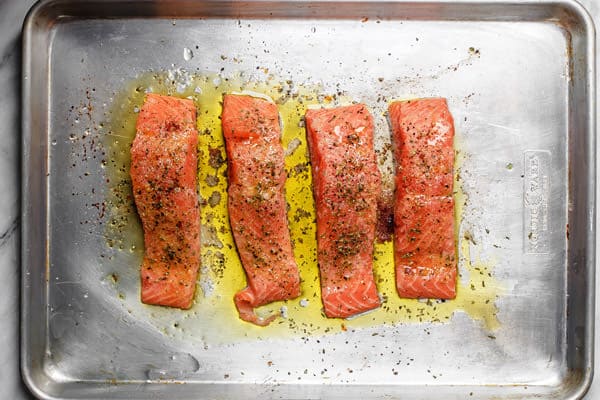 Salmon fillets placed on a baking sheet and drizzled with olive oil