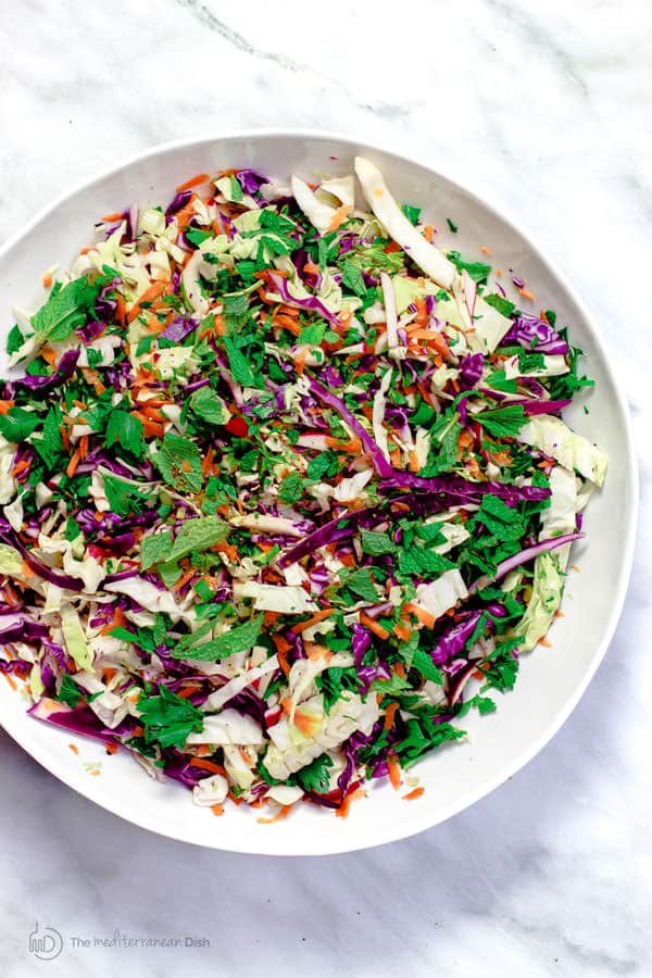 Coleslaw contents in a bowl tossed with dressing