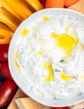 Tzatziki cucumber yogurt sauce in a bowl with a side of sliced vegetables