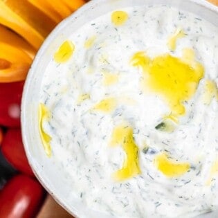 Tzatziki cucumber yogurt sauce in a bowl with a side of sliced vegetables