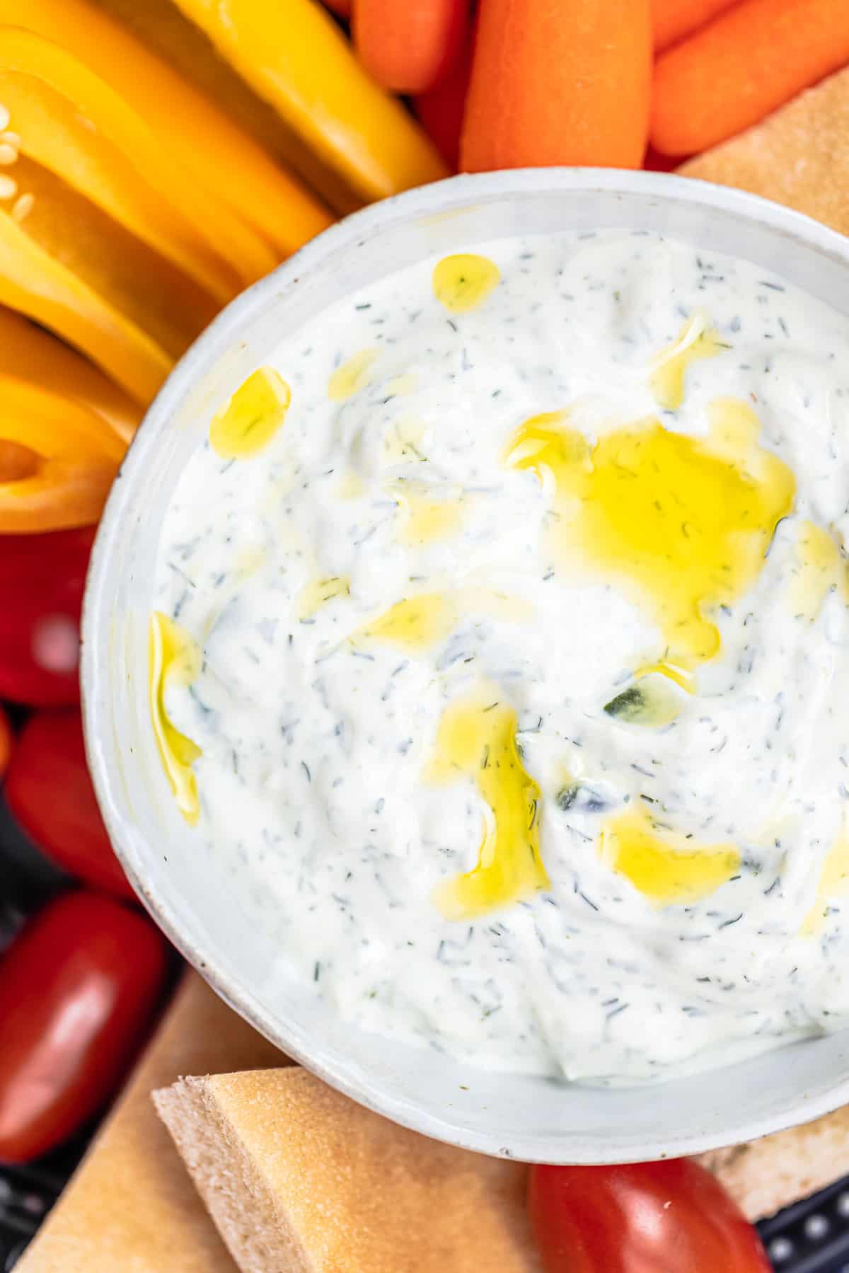 Tzatziki cucumber yogurt sauce in a bowl with a side of sliced vegetables