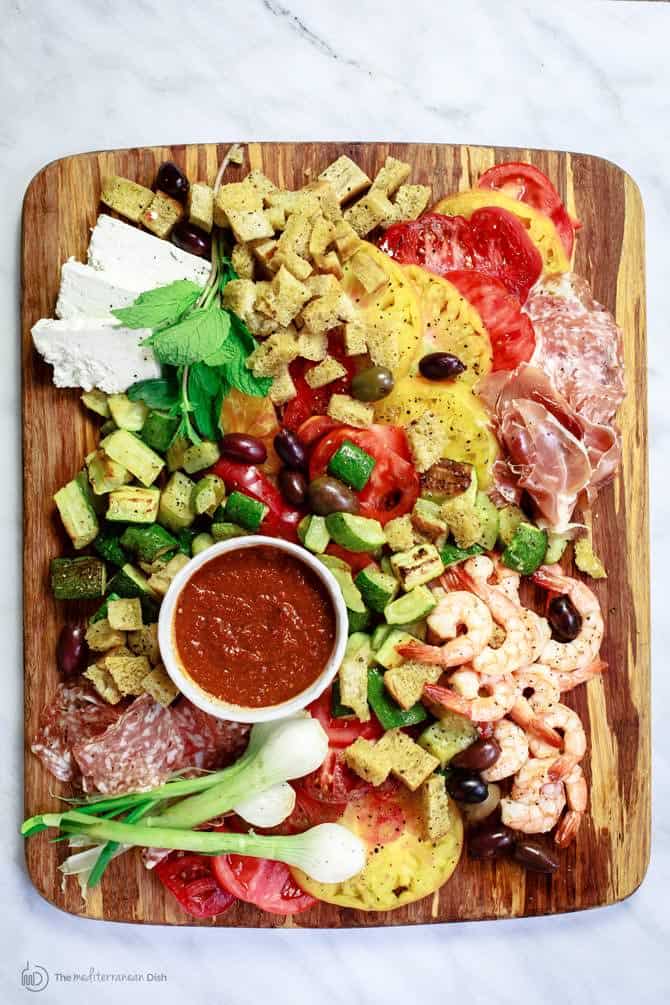 Shrimp and Zucchini Panzanella Salad served on a cutting board with sauce for dipping