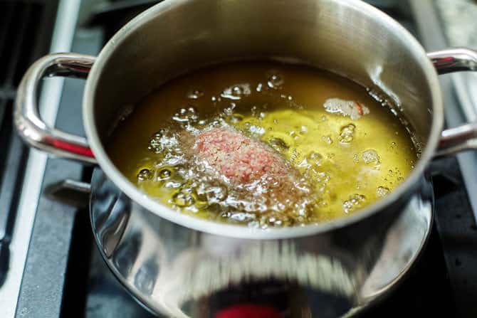 Stuffed kibbeh added to a pot of hot oil for frying