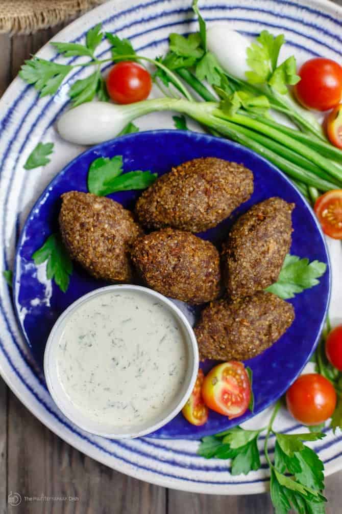 Kibbeh on a plate served with Greek dip