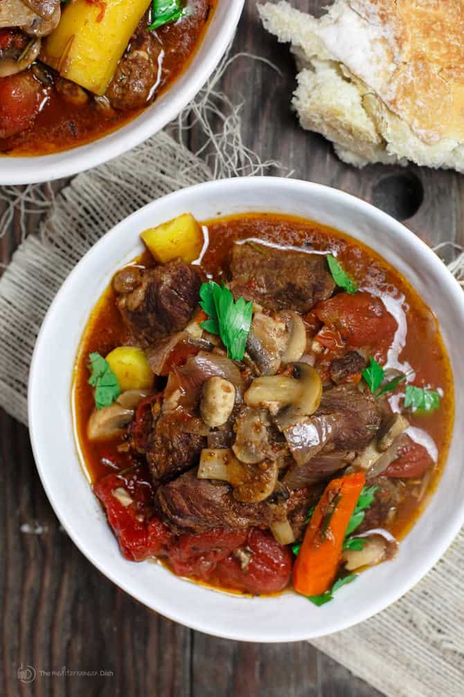 Crock Pot Italian Beef Stew Recipe | The Mediterranean Dish. This is a family favorite! Beef stew that's been slow cooked to tender perfection in a special wine broth with loads of carrots, mushrooms and aromatics. Packed with flavor from garlic, onions, and fresh herbs. Best part, it takes only 15 minutes to prep, and the crock pot does all the heavy lifting. This is the prefect beef stew! A must-try from TheMediterraneanDish.com