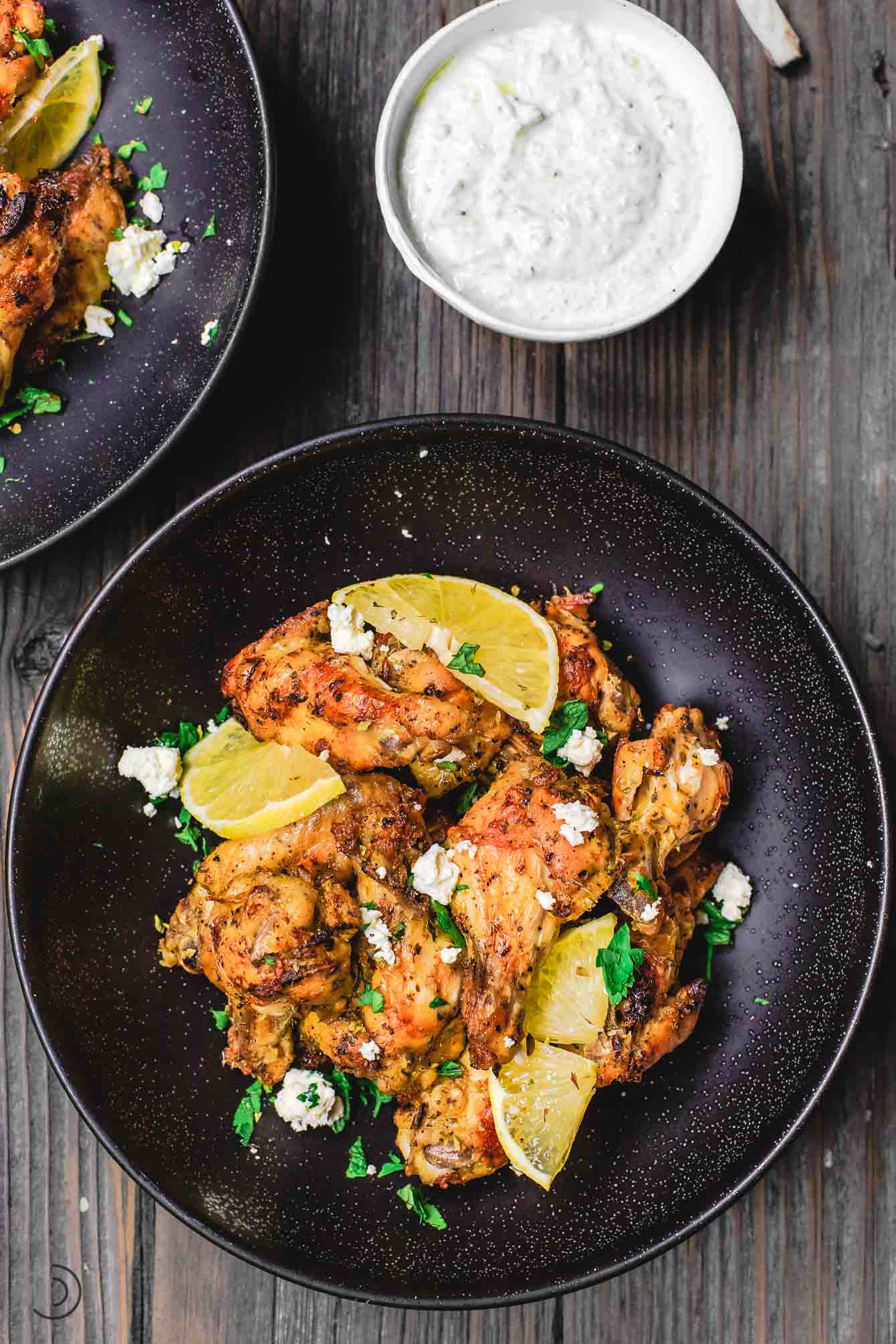 Baked wings in a bowl with a side of Tzatziki sauce