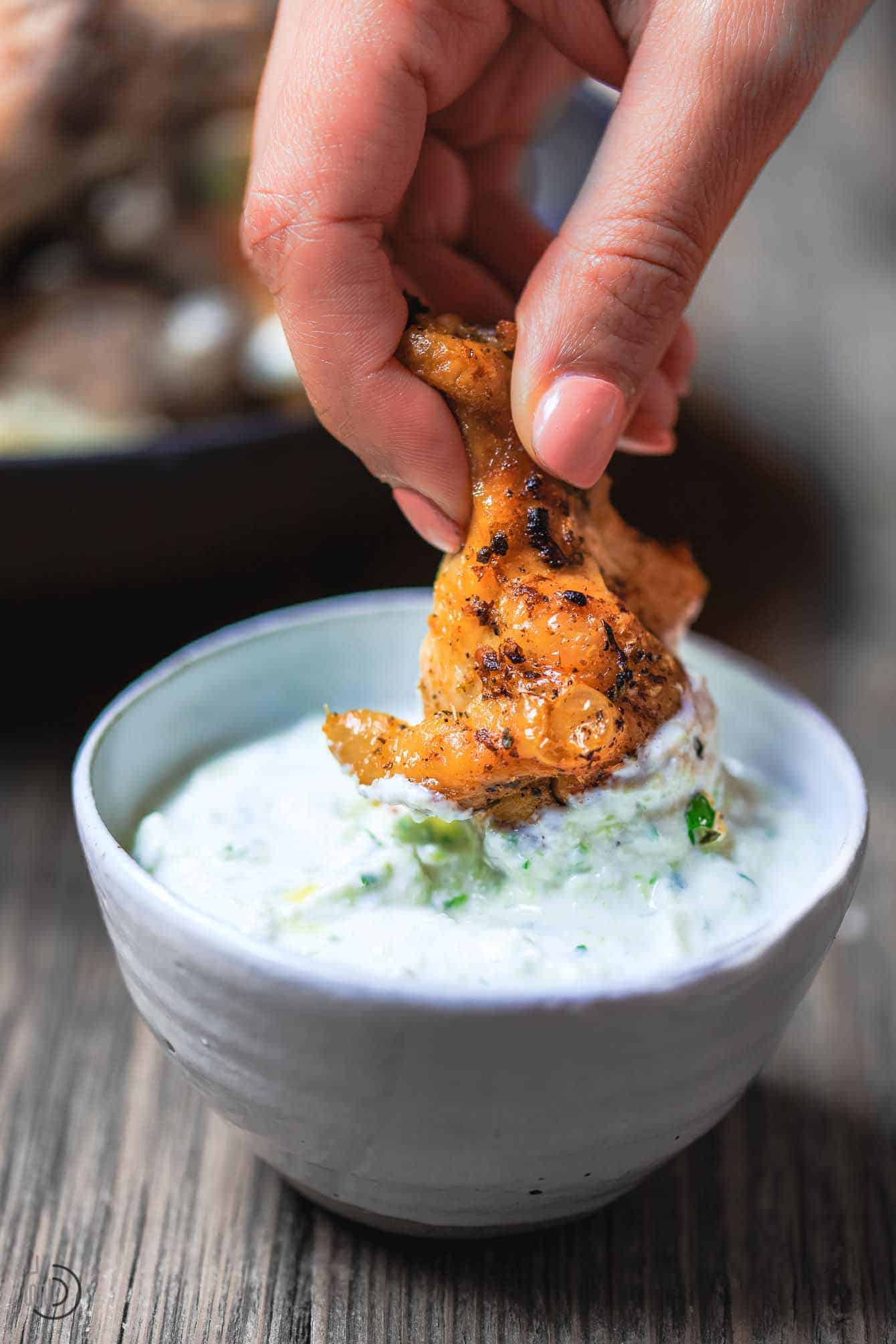 baked wing being dipped in Tzatziki sauce