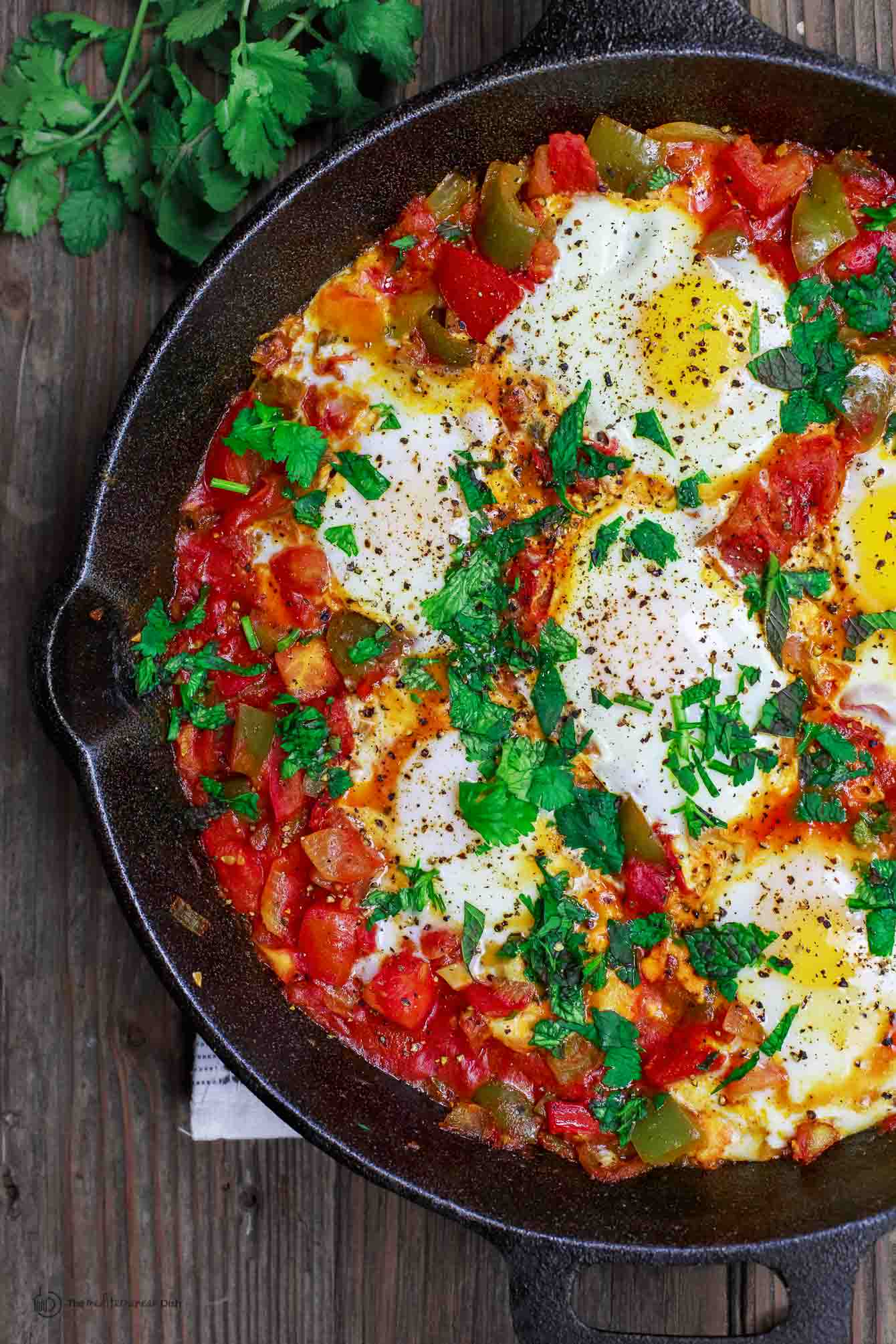 Simple Shakshuka Recipe | The Mediterranean Dish. Shakshuka is a delicious Middle Eastern dish of eggs poached in a spiced, saucy tomato stew. Perfect for breakfast, lunch or dinner! All you need to add is your favorite bread. This is a simple vegetarian recipe that you can make in less than 30 minutes! My family's favorite. And feeds a crowd on a small budget. See the recipe on TheMediterraneanDish.com