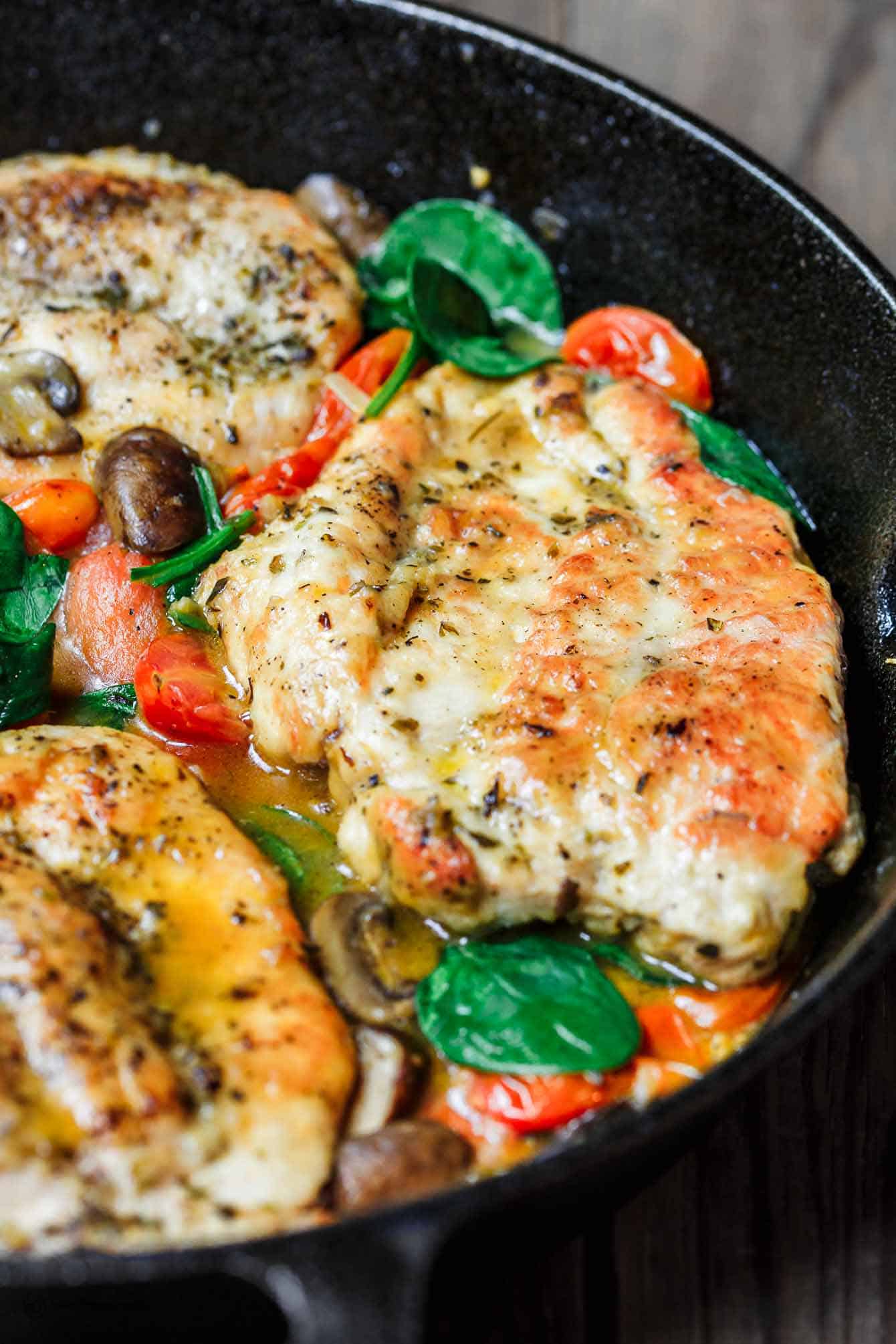 30-Minute Italian Skillet Chicken Recipe with Tomatoes and Mushrooms | The Mediterranean Dish. Flavor packed chicken breasts cooked in white wine with mushrooms, tomatoes and more! The perfect weeknight dinner in minutes! See the recipe on TheMediterraneanDish.com