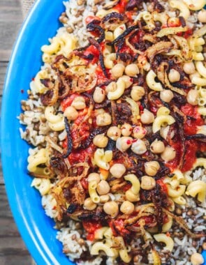 Egyptian Koshari Recipe | The Mediterranean Dish. Hands down a family favorite. A comforting bowl of spiced lentils and rice with chickpeas, tiny pasta, and tomato sauce. Topped with thin crispy onion rings. A tasty, budget friendly, vegan recipe! See it on TheMediterraneanDish.com