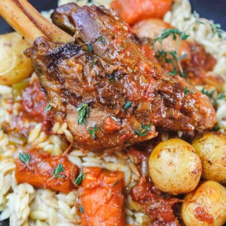 Mediterranean-Style Wine Braised Lamb Shanks Recipe | The Mediterranean Dish. Braising and slow cooker instructions included! Spiced lamb shanks cooked in a red wine and tomato sauce with vegetables, aromatics and fresh herbs! A family favorite for Easter or your next special dinner! See it on TheMediterraneanDish.com