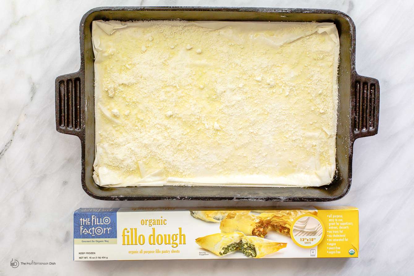 Fillo dough added to baking pan brushed with oil/butter mix