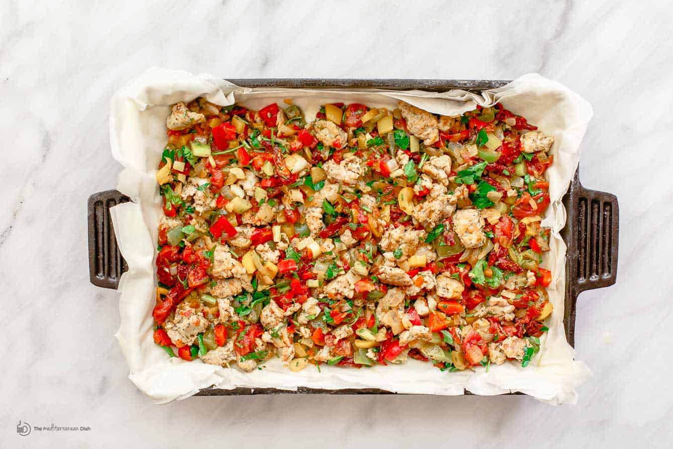 Vegetable and sausage mix added to fillo dough in baking pan