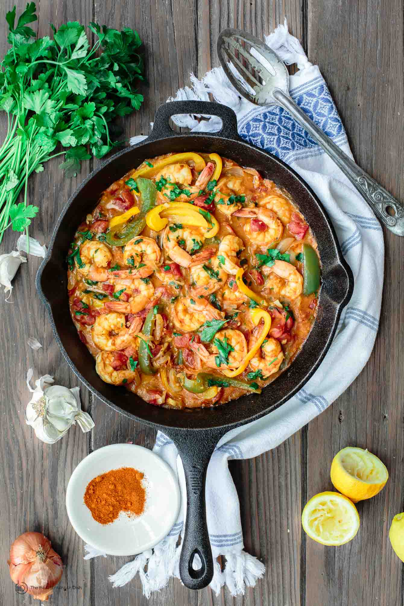 Shrimp with bell peppers and shallots in sauce served on a table