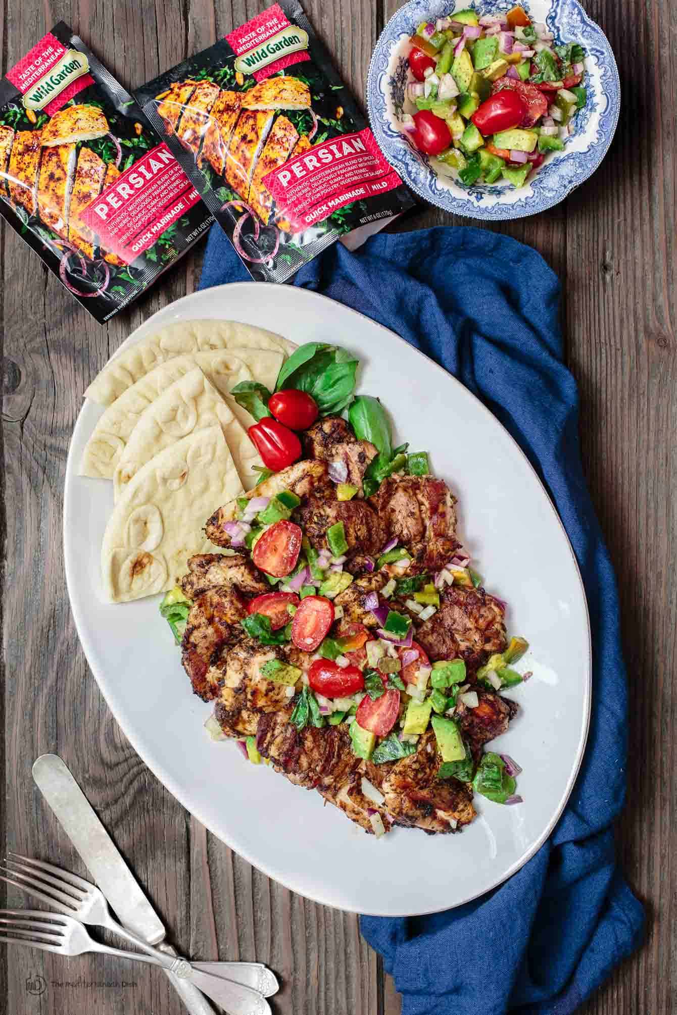 Barbecue Chicken Thighs served with a side of Pita Bread, Bag of Persian marinade shown in photo.