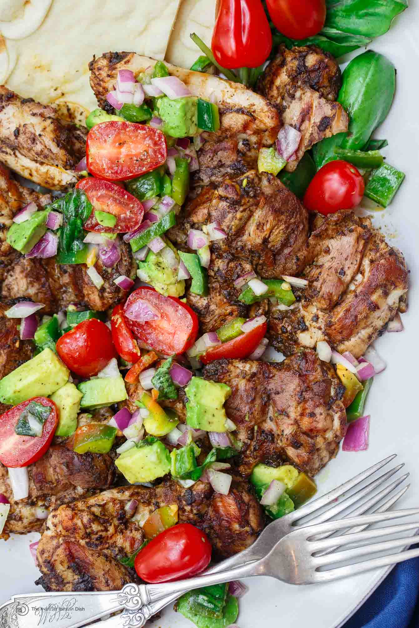 Persian-Style Barbecue Chicken Thighs topped with avocado, cherry tomatoes and onion