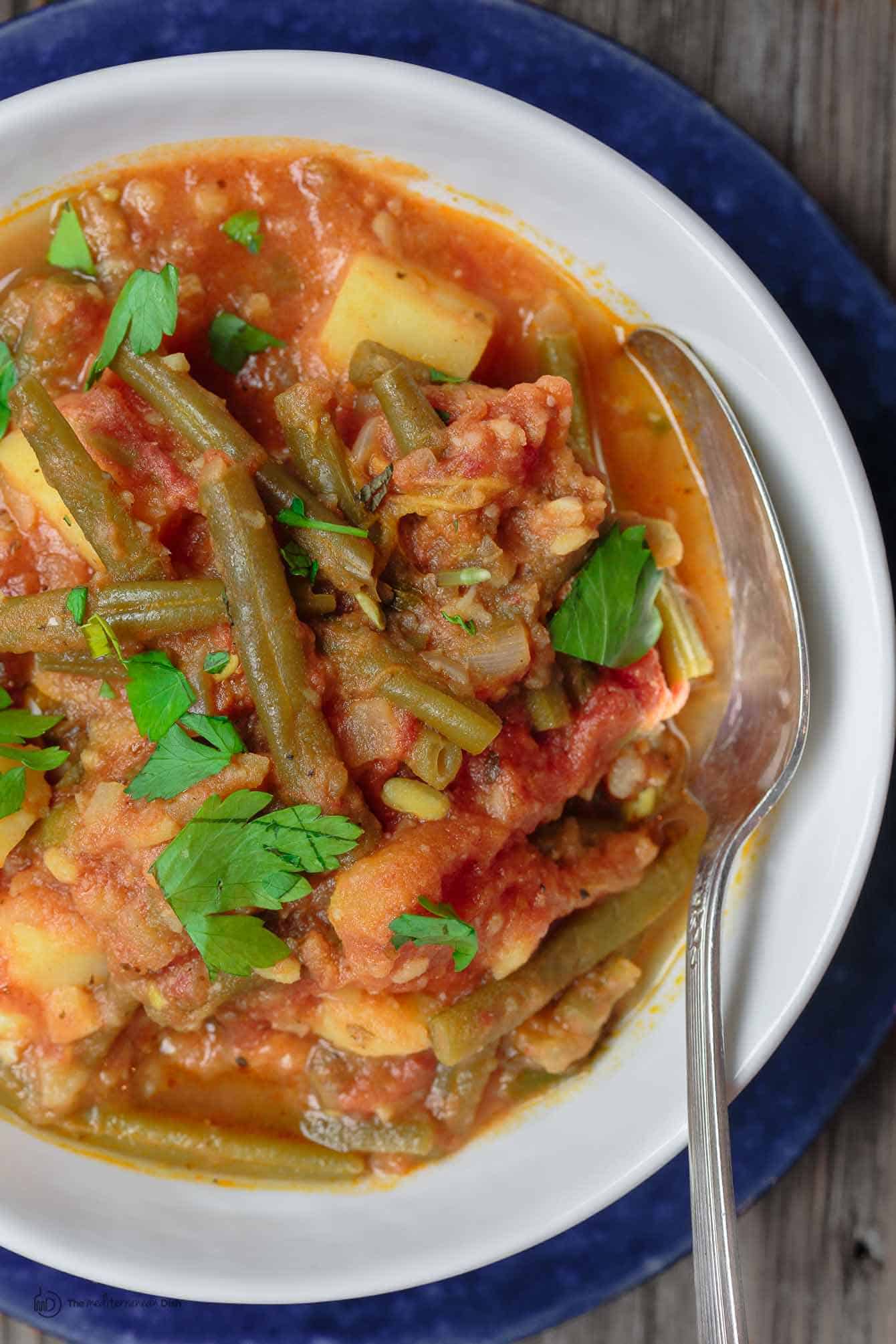 Greek Green Beans (Fasolakia) | The Mediterranean Dish. Braised Greek green beans with tomatoes, olive oil, aromatics and spices. Tender green beans, so velvety in texture. Satisfying and every bit flavor-packed. A healthy vegan entree or side dish that is so simple to make. Get the recipe on TheMediterraneanDish.com