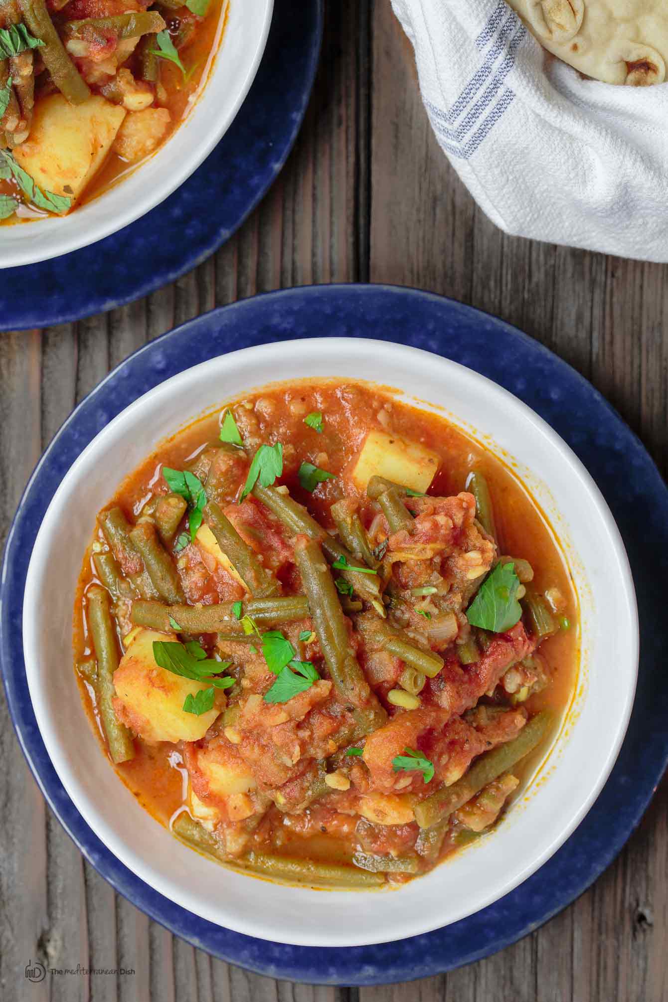 Greek Green Beans (Fasolakia) | The Mediterranean Dish. Braised Greek green beans with tomatoes, olive oil, aromatics and spices. Tender green beans, so velvety in texture. Satisfying and every bit flavor-packed. A healthy vegan entree or side dish that is so simple to make. Get the recipe on TheMediterraneanDish.com