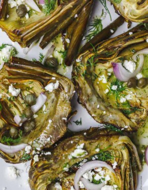 Mediterranean-style roasted artichokes topped with shallots, feta, capers, and dill