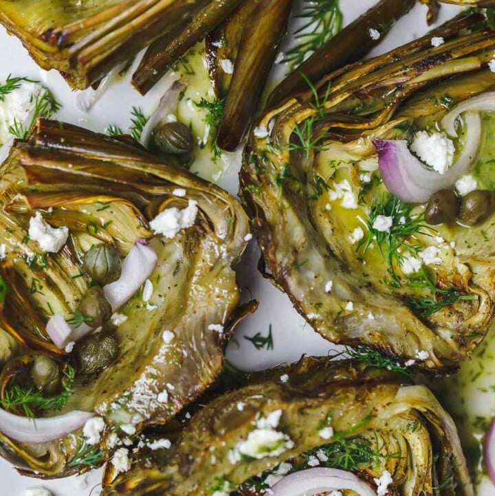 Mediterranean-style roasted artichokes topped with shallots, feta, capers, and dill