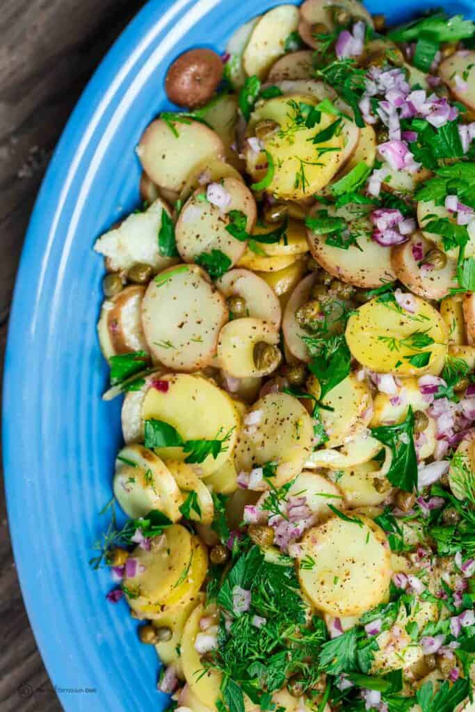 Mustard potato salad served on platter, garnished with dill and parsley