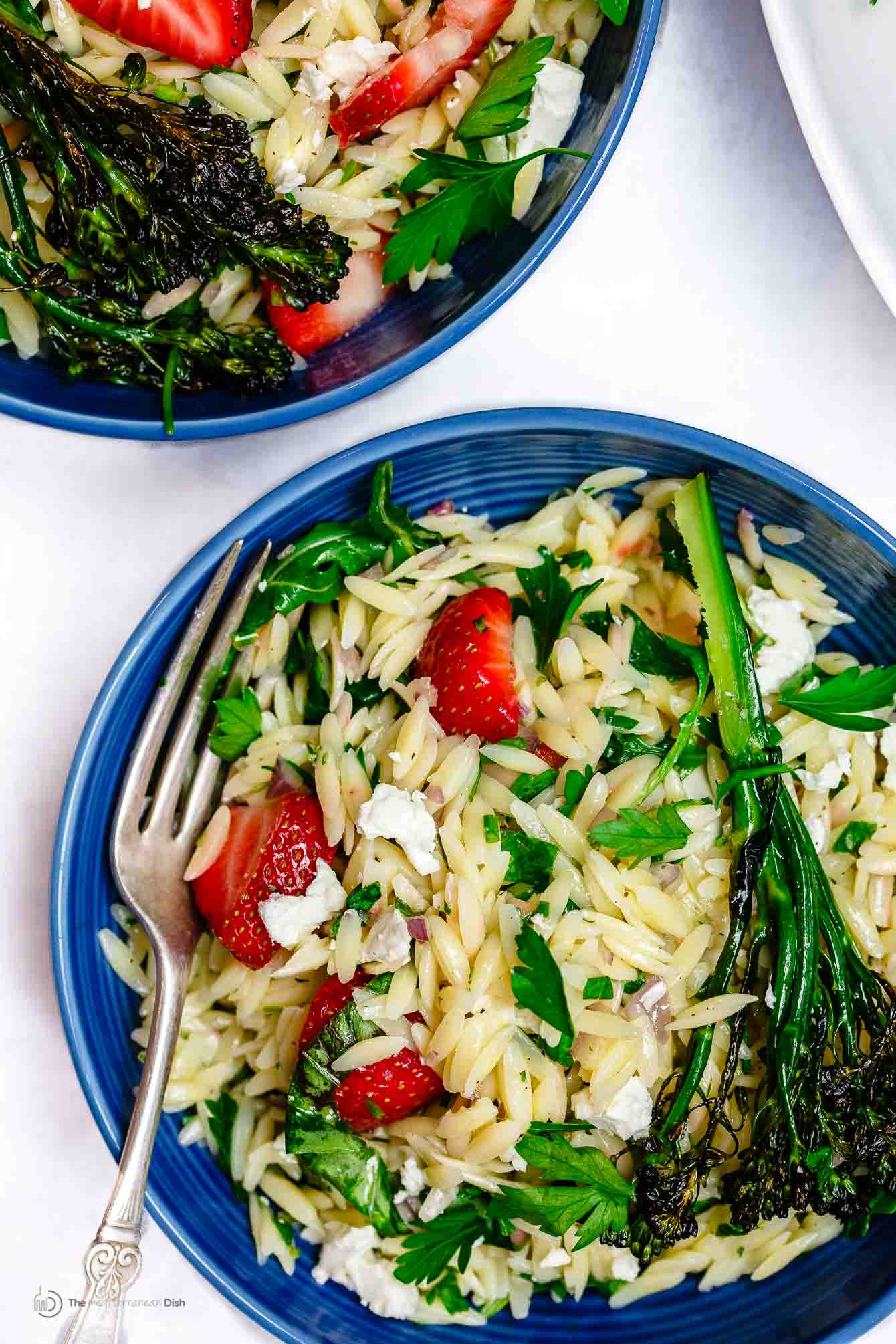 Bowl of Mediterranean Strawberry Orzo Pasta Salad garnished with feta cheese