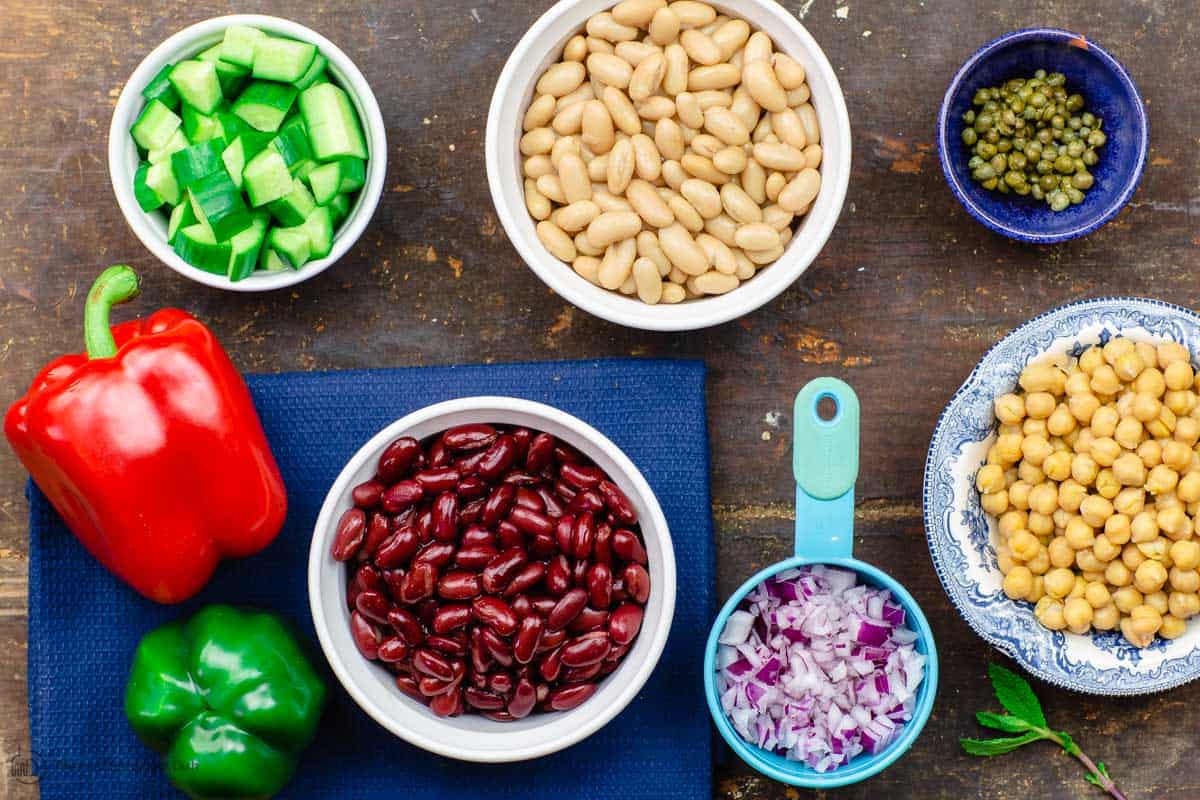 Ingredients for Mediterranean three bean salad: beans, fresh vegetables, onion, capers and mores