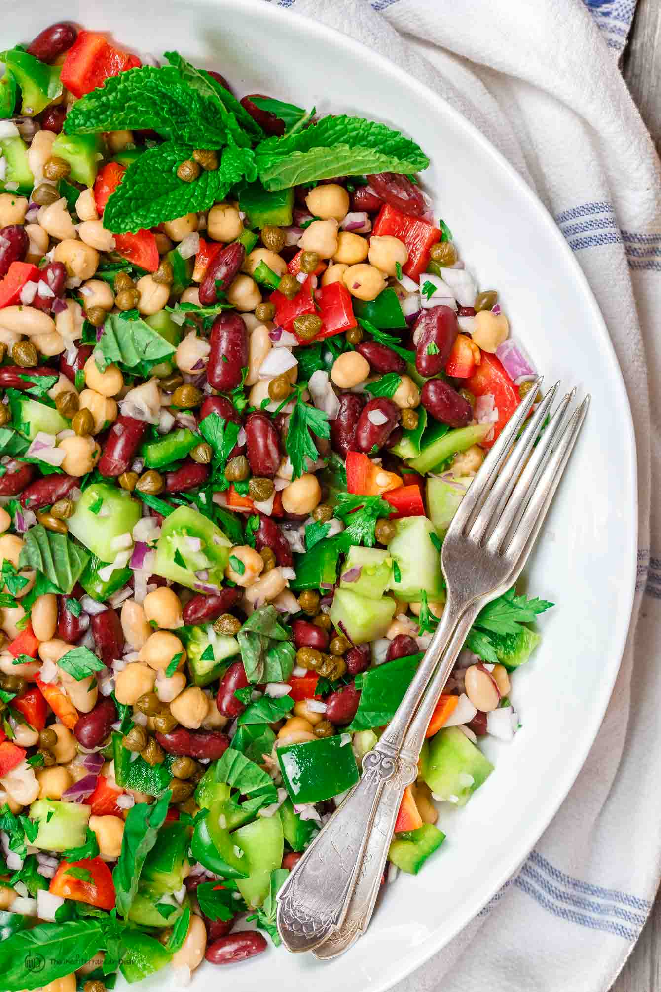 Mediterranean style three bean salad with bell peppers, fresh herbs, capers, and dijon viniagrette