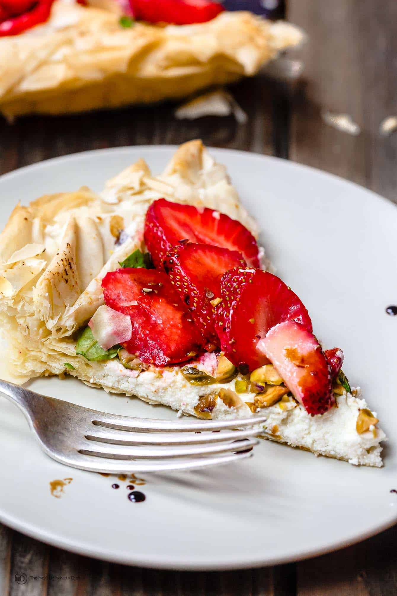 Slice of Strawberry Tart garnished with crushed nuts