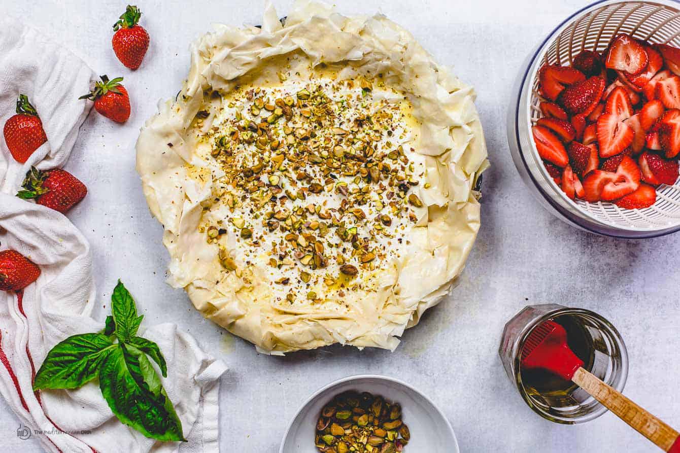 Pistachio nuts sprinkled onto greased fillo dough in cooking pan