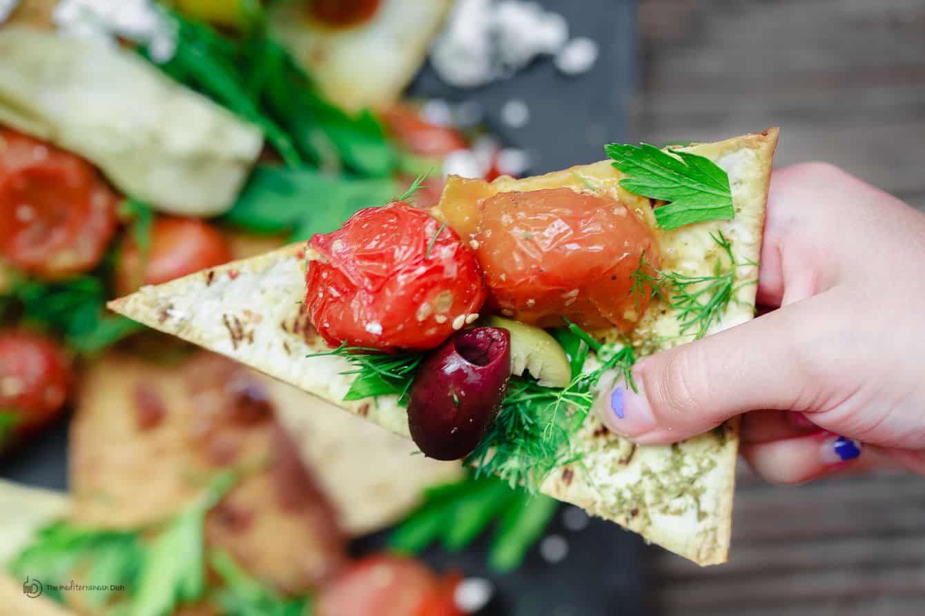 One piece of Mediterranean Nachos topped with vegetables and garnished with parsley