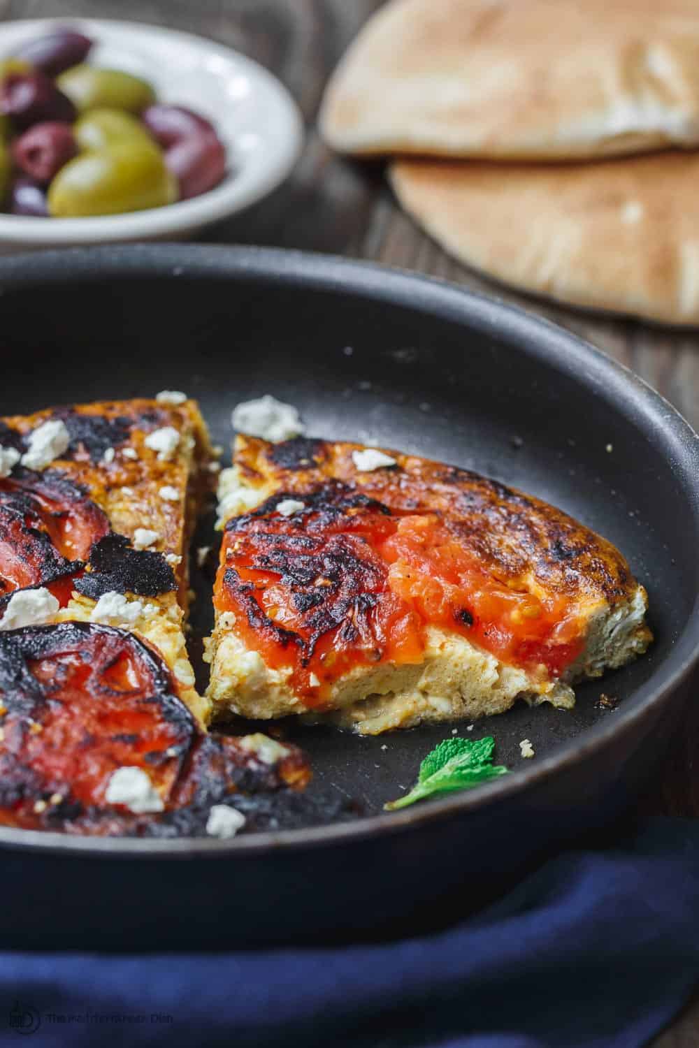 Slice of Open-Faced Greek Omelet served with olives and bread