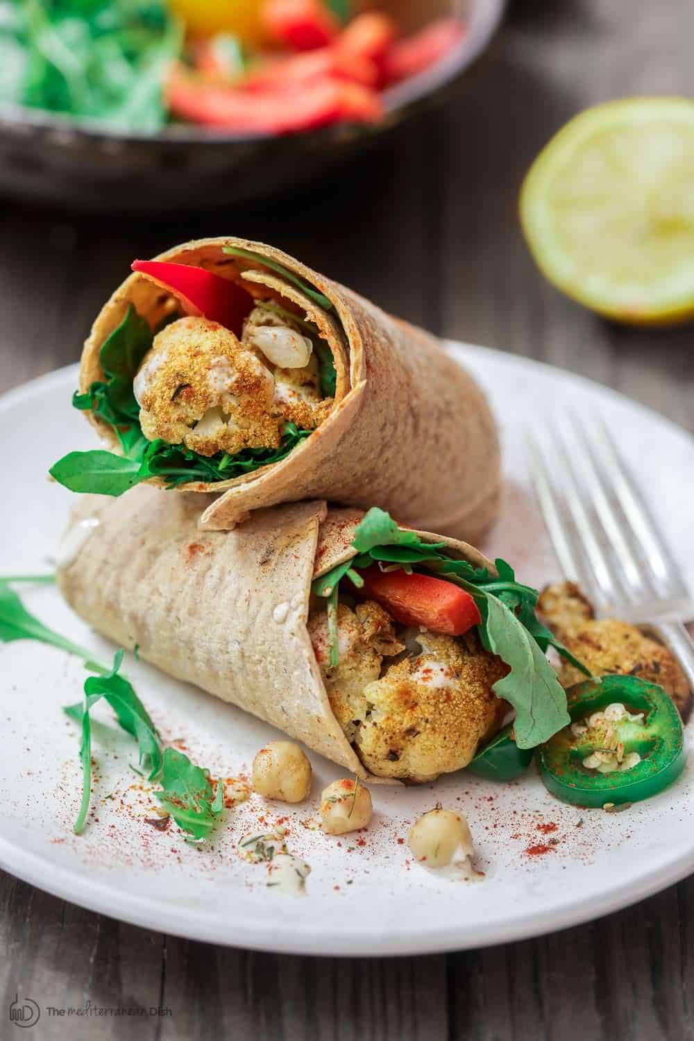 Vegan Wraps containing cauliflower serves on a plate with arugula garnish