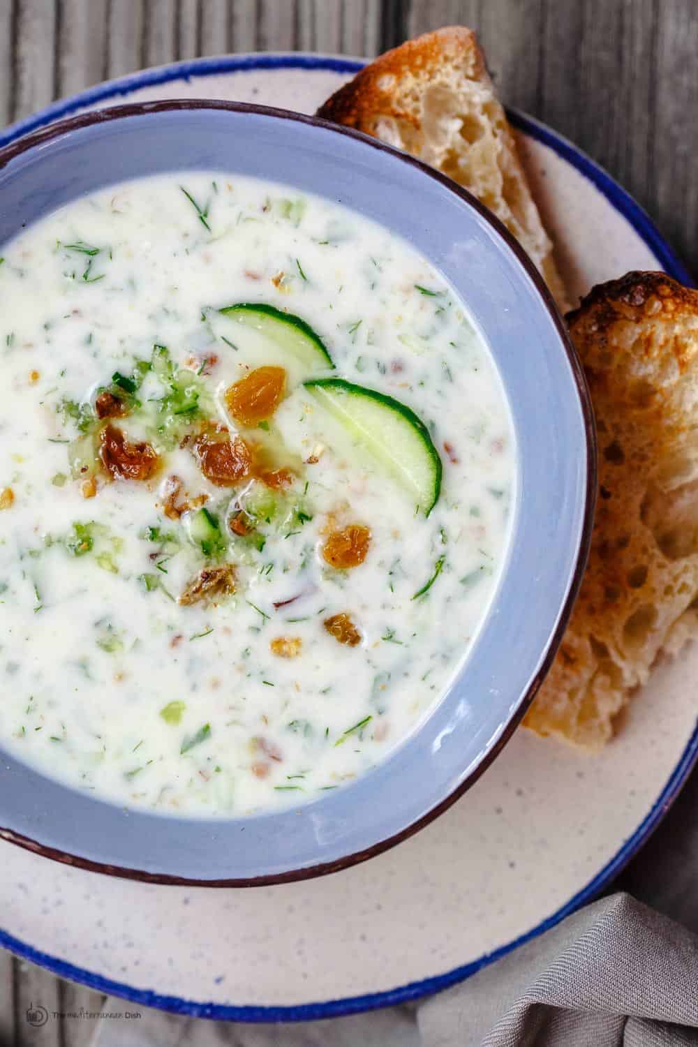 Persian Chilled Cucumber Soup (Abdoogh Kiar) | The Mediterranean Dish. A cold cucumber soup in a yogurt base with lots of fresh herbs, toasted walnuts, and raisins. Think detox soup to help you cool off and rest your body! See the recipe on TheMediterraneanDish.com