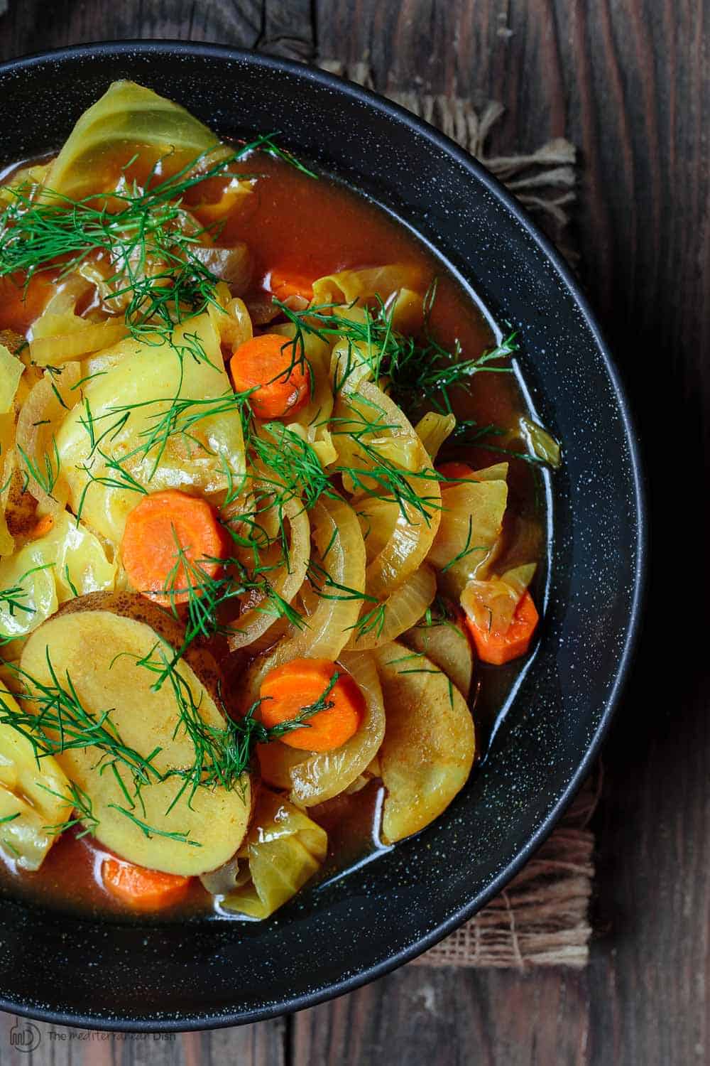 One bowl of cabbage soup, garnished with fresh dill 